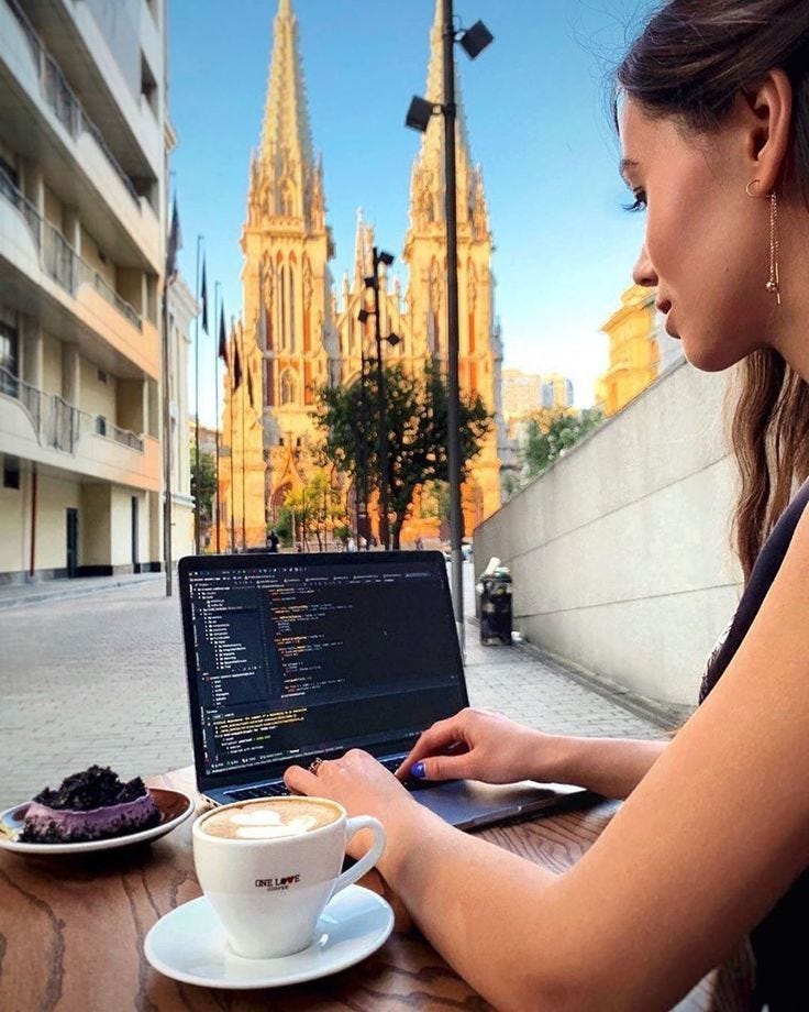 This may contain: a woman sitting at a table with a laptop and cup of coffee in front of her This may contain: a woman sitting at a table with a laptop and cup of coffee in front of her