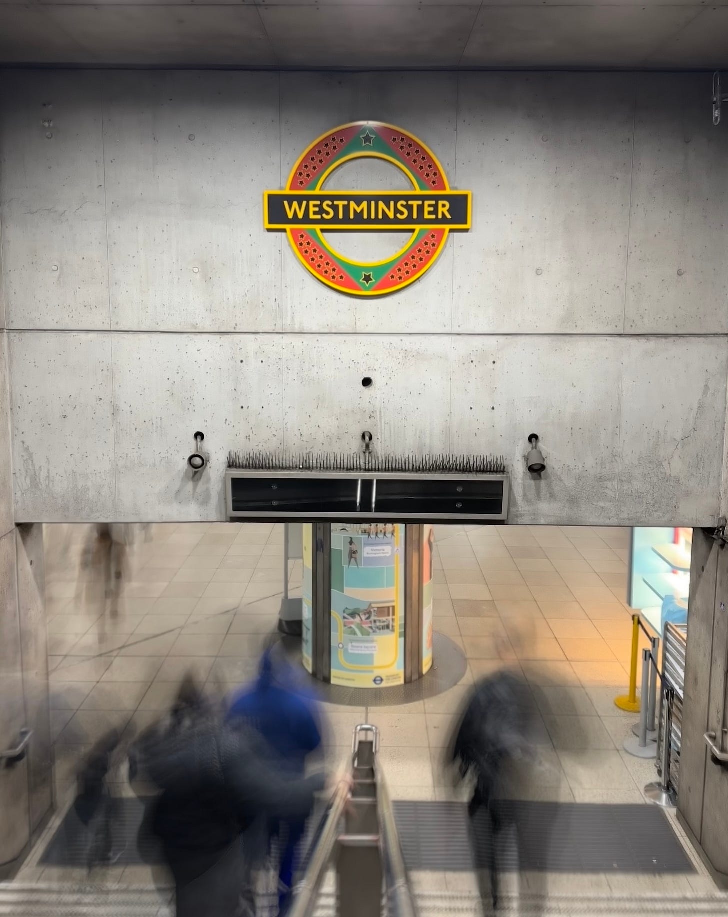 Entrance 4 at Westminster Underground station in London. The famous London Underground roundel is slightly different because this version is a permanent artwork made by the artist Larry Achiampong and uses the Afrofuturist symbols of red, green gold and black stars.