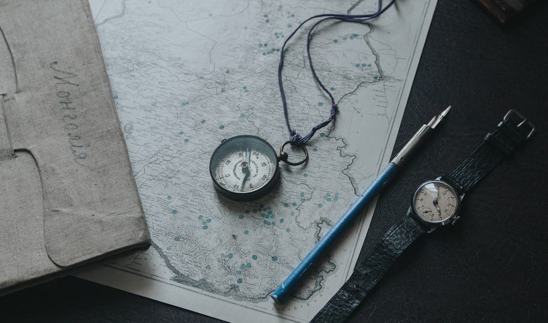 blue and white ballpoint pen beside silver round analog watch