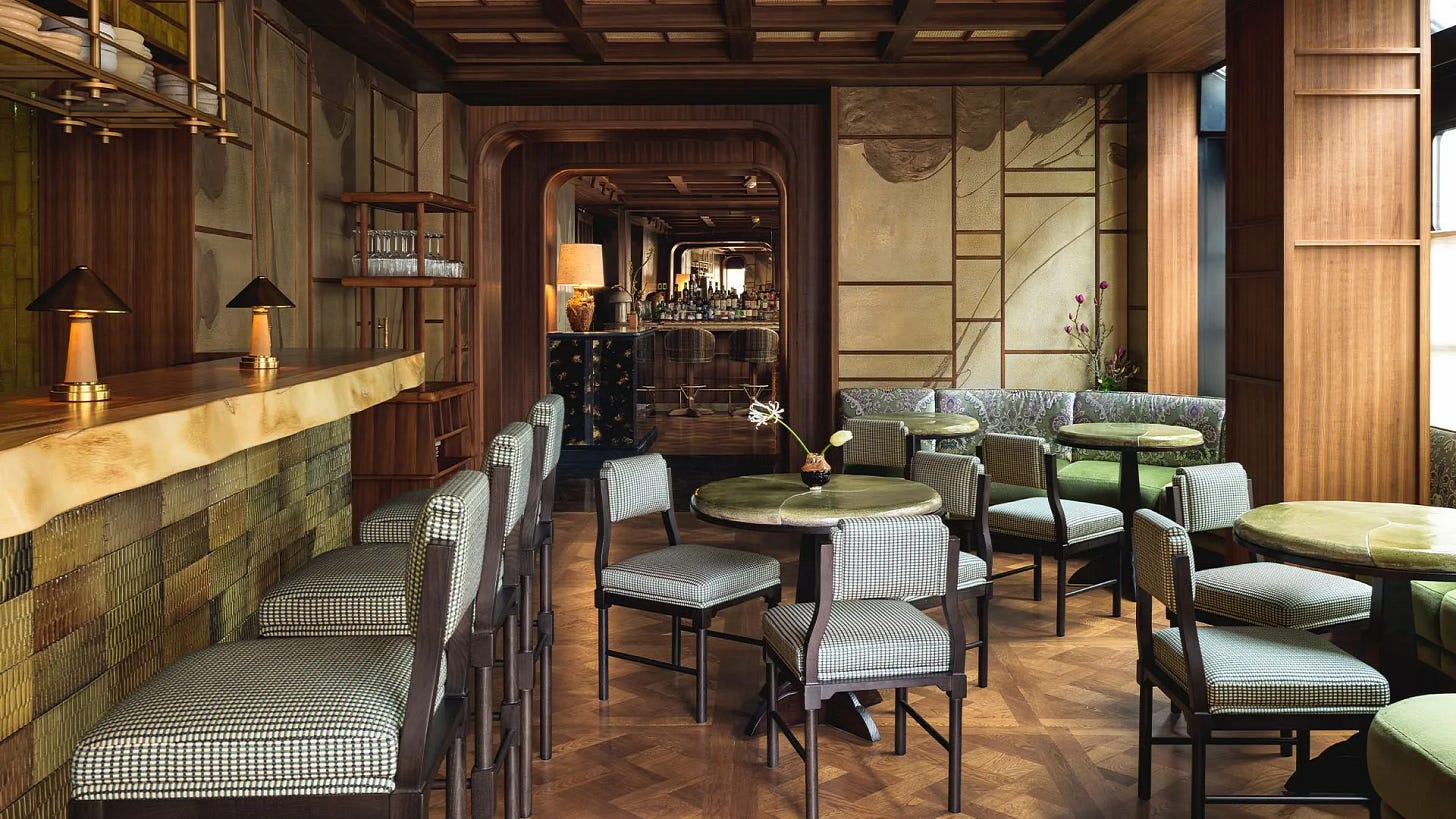 Hôtel Hana in Paris with a brass-fronted bar, dark wood paneling, patterned seating, soft lighting, and intimate café tables.