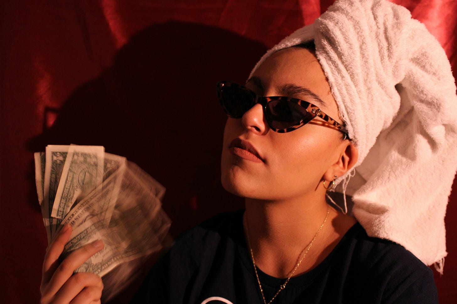 A woman in shades fans herself with a handful of banknotes
