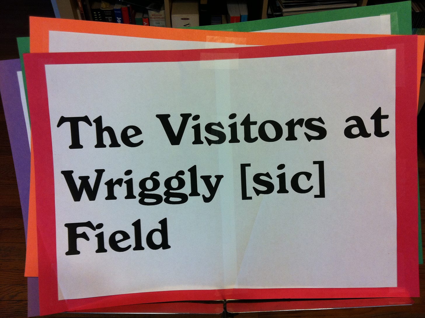A sign mounted on red construction paper reads: "The Visitors at Wriggly [sic] Field"