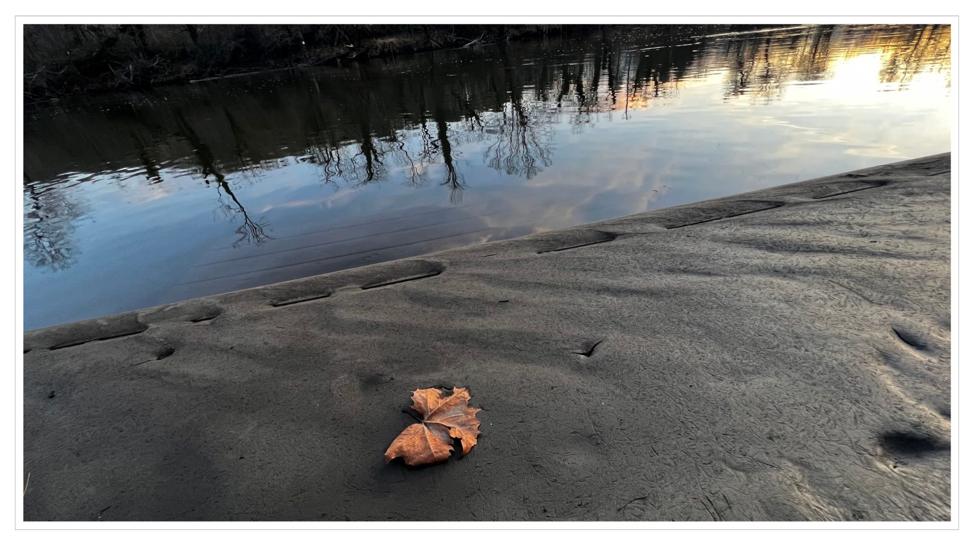 mud-covered dock by calm river, sunset