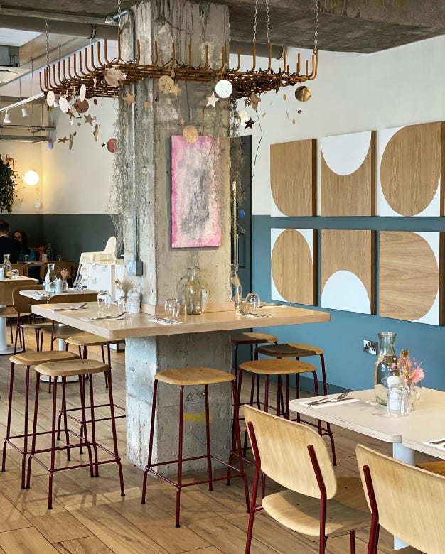 A photo of the cafe, with wooden stools and countertops, and decorative mobiles hanging from the ceiling