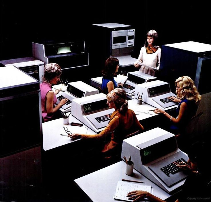 This may contain: there are many women sitting at desks with computers