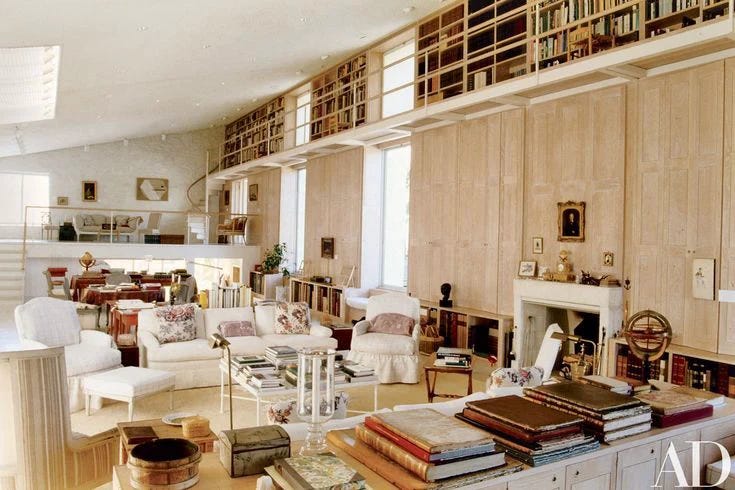 This may contain: a living room filled with lots of furniture next to a fire place and bookshelf