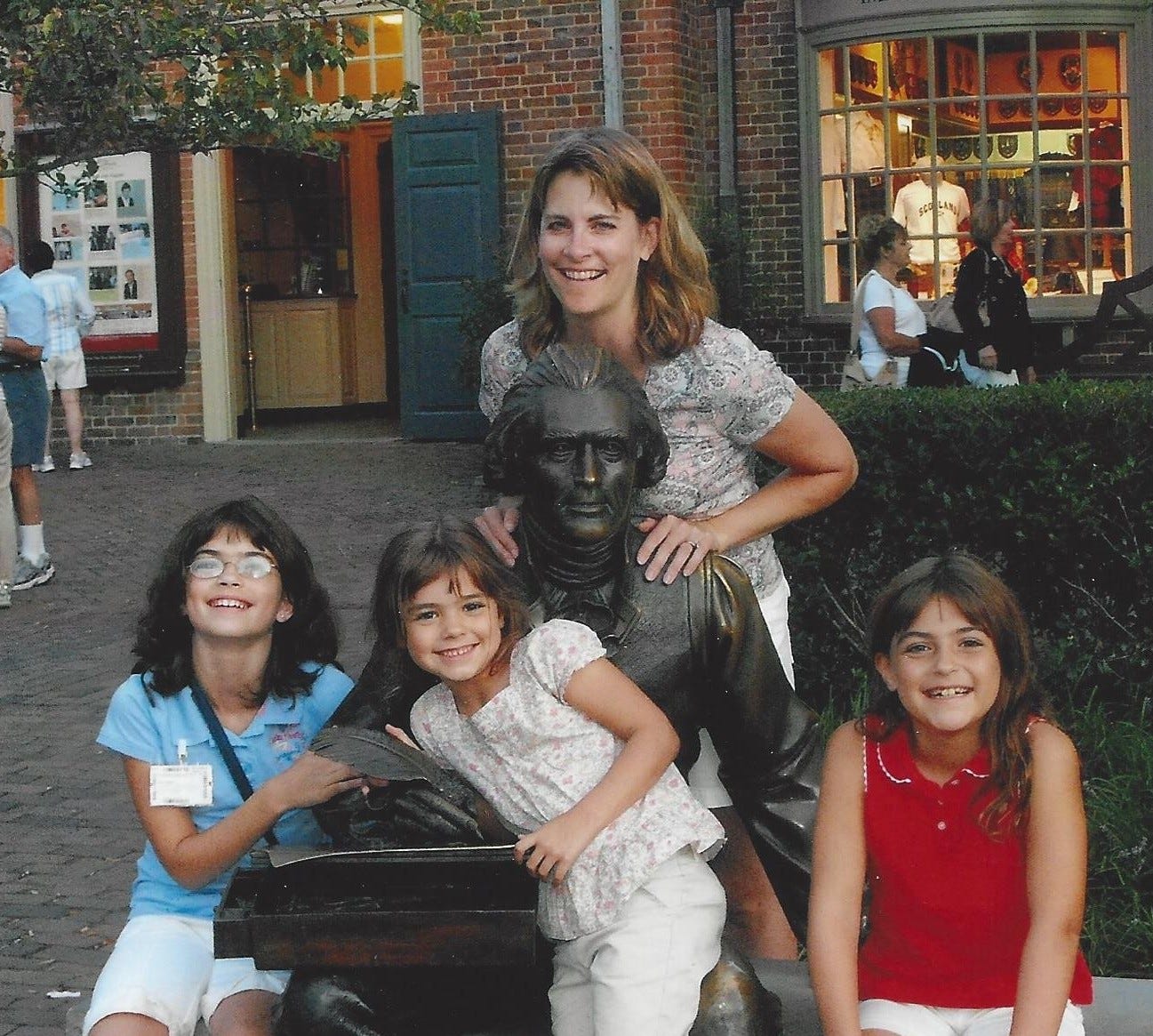 Mom and three daughters posed with a statue of Thomas Jefferson in Colonial Williamsburg