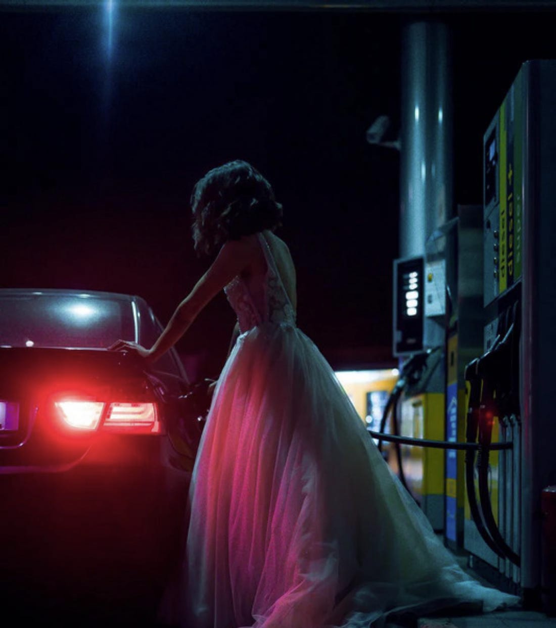 Woman in wedding dress pumping gas. Woman in wedding dress pumping gas.