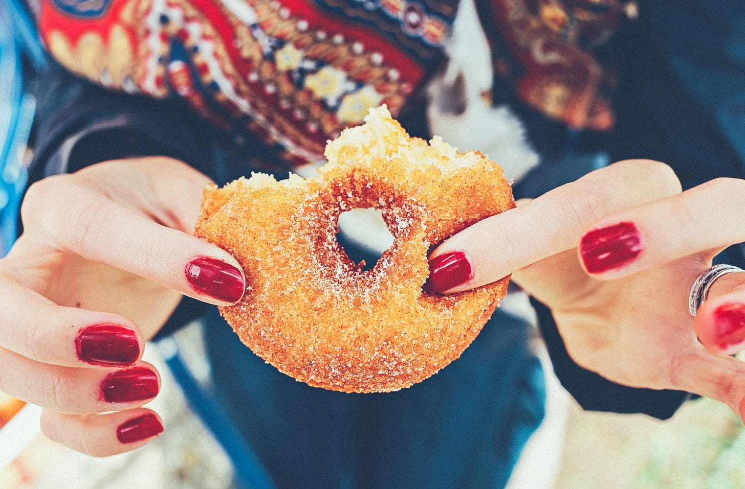 A woman holding half of a donut.