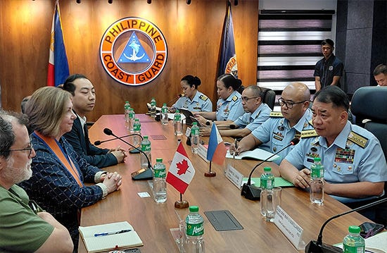 Assistant Deputy Minister (Public Affairs) Geneviève Binet and Canadian delegation members sit across from Philippine Coast Guard officers at a conference table, with Canadian and Philippine flags displayed between them.