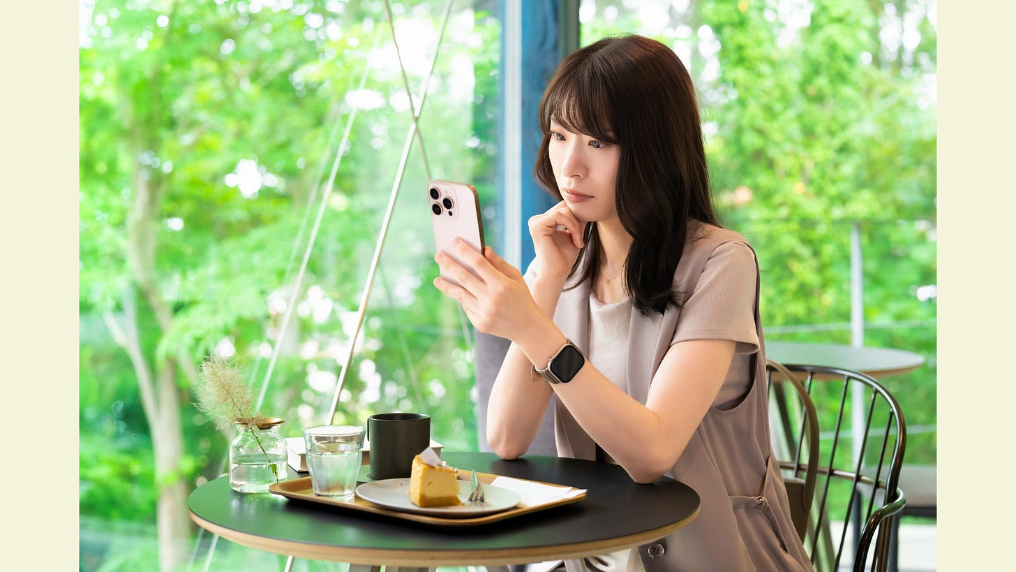 A woman in a café, looking at her phone and thinking A woman in a café, looking at her phone and thinking