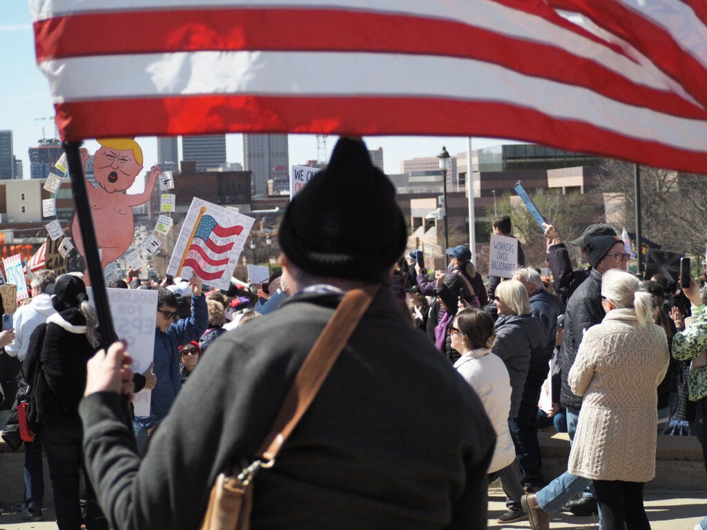 David Russell sat holding an American flag on the steps of the Iowa Capitol as part of the "No Kings" protest in Des Moines March 28, 2026. (Photo by Robin Opsahl/Iowa Capital Dispatch) David Russell sat holding an American flag on the steps of the Iowa Capitol as part of the "No Kings" protest in Des Moines March 28, 2026. (Photo by Robin Opsahl/Iowa Capital Dispatch)