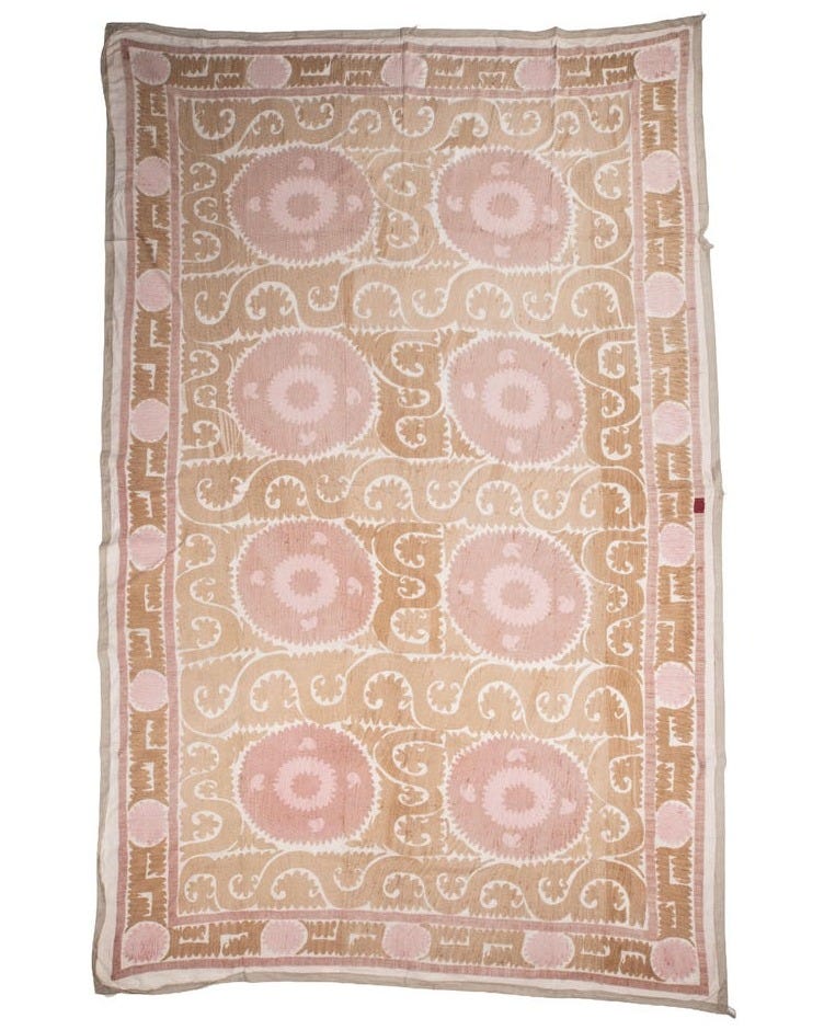 May include: A rectangular textile wall hanging featuring a light beige background with a repeating pattern of large, circular, pale pink floral motifs. The design includes intricate, swirling tan embroidery throughout, framed by a decorative border.