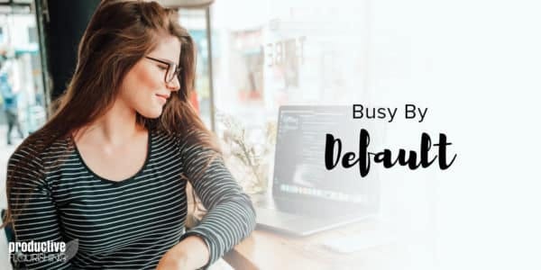 Woman in glasses, looking over her computer. Text overlay: Busy by Default Woman in glasses, looking over her computer. Text overlay: Busy by Default