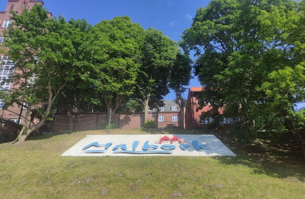 A large sign on a grassy bank spells out Malbork.