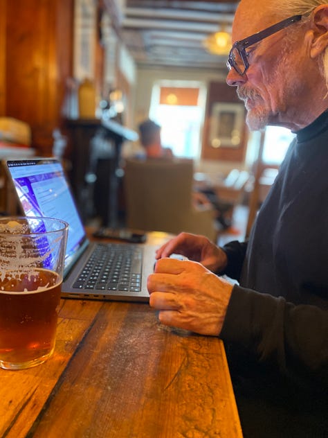 The KIngs Head hotel with people smiling outside and working on a laptop inside the bar