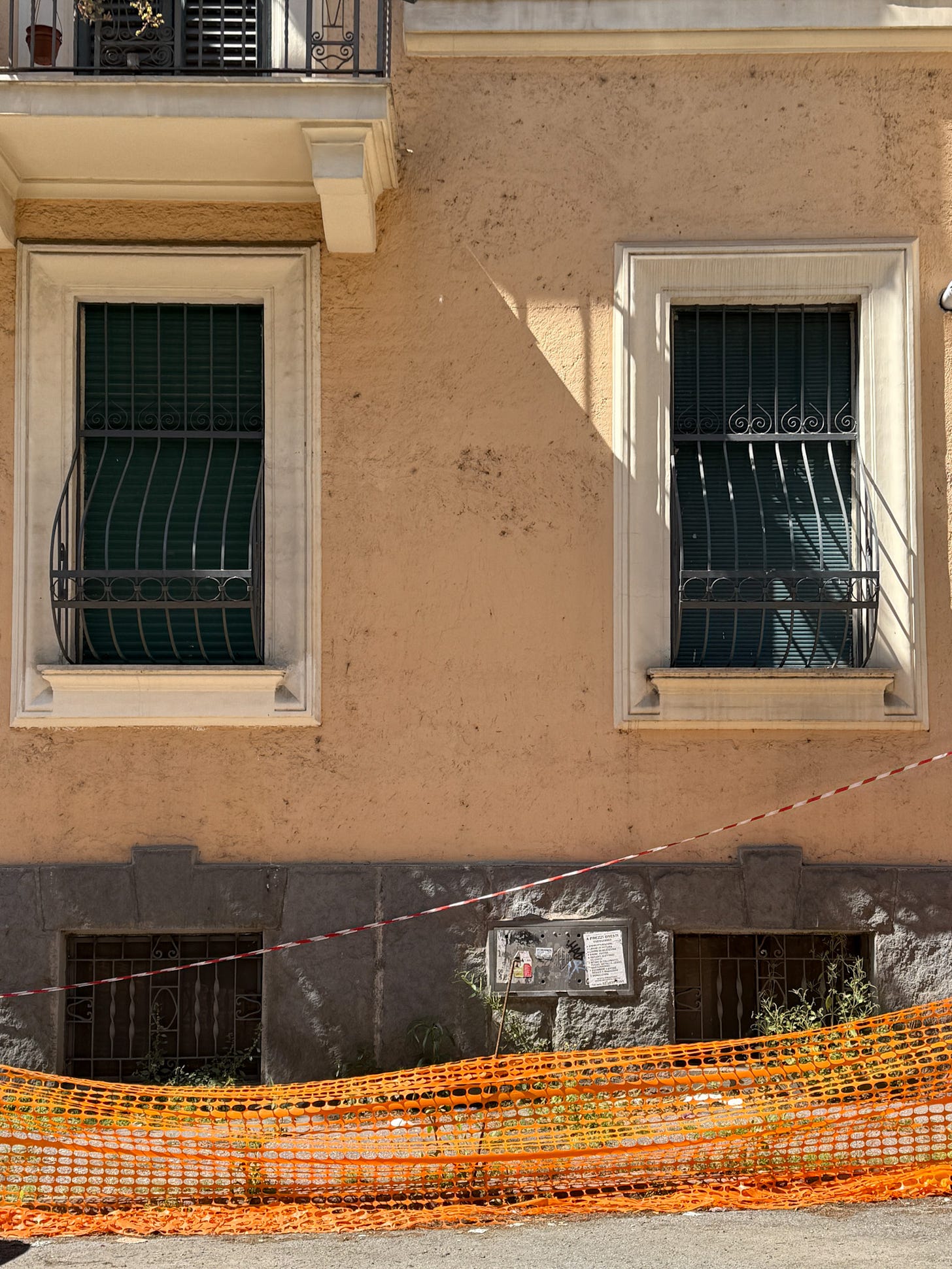 Two-paneled diptych of closed wooden shutters in warm light; horizontal shadows stretch across the facade.