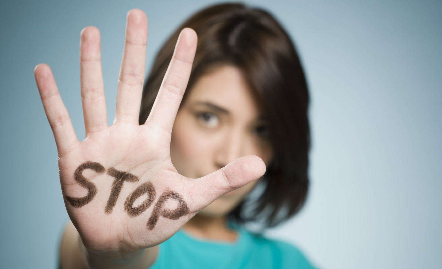 a woman holding her open hand into the camera. IN the palm of her hand it says STOP referring to intimate partner violence
