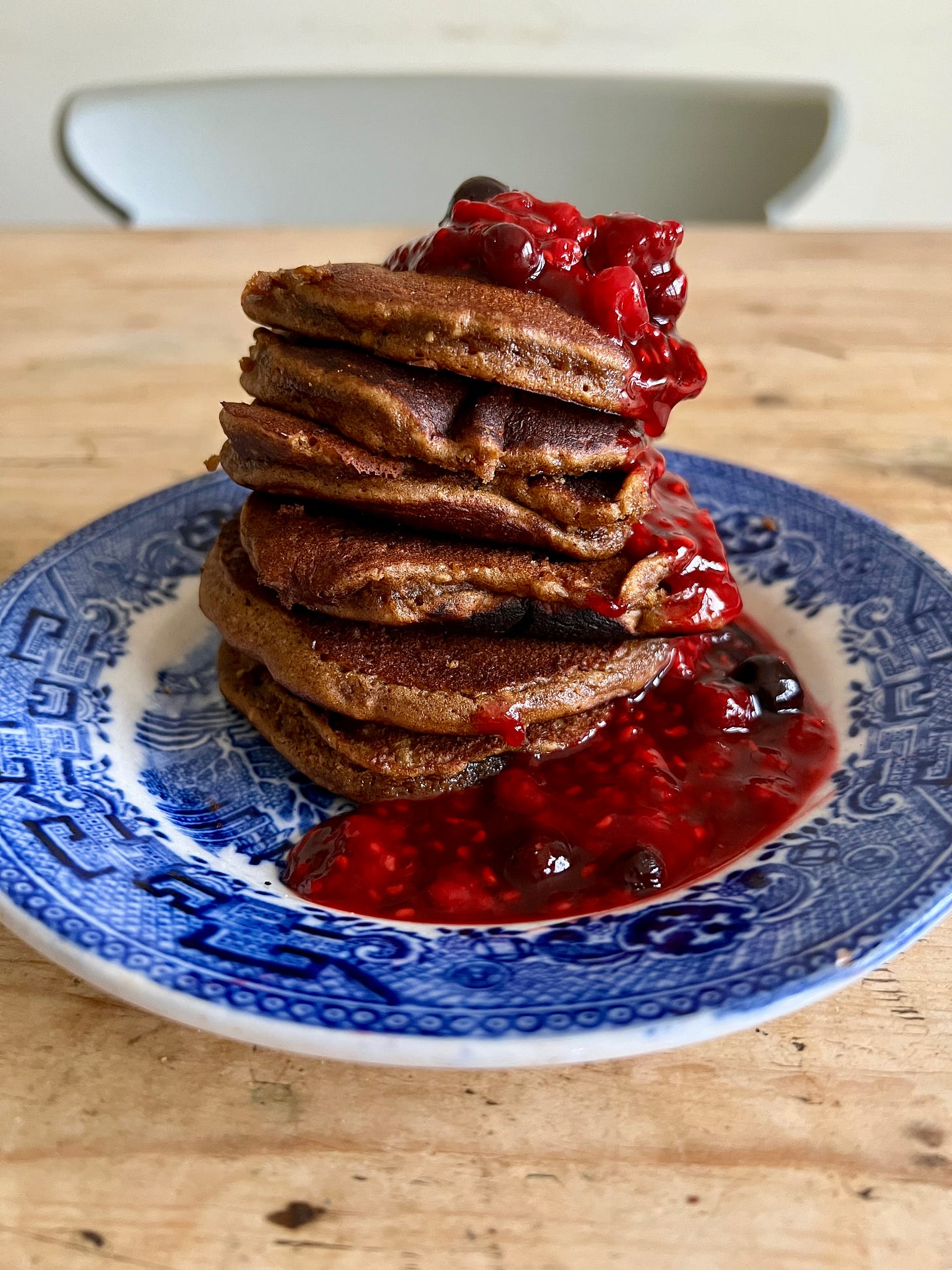 Stack of brown pancakes drizzled with a berry compote