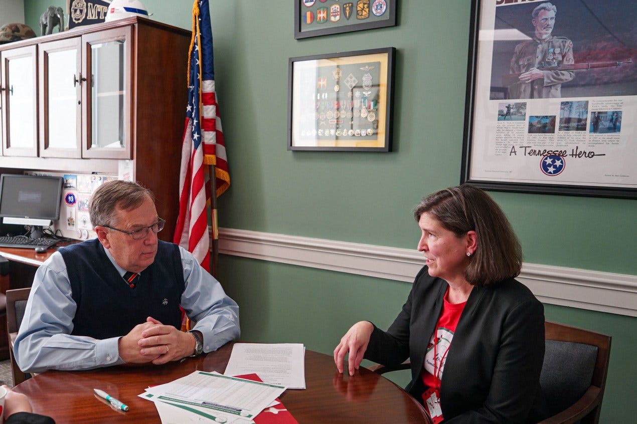 Barb Dentz (right), sits beside state representative, Sam Whitson (left), in an office room. The walls are an olive green and are adorned by framed medals. An American flag stands in the corner, behind them. Barb Dentz (right), sits beside state representative, Sam Whitson (left), in an office room. The walls are an olive green and are adorned by framed medals. An American flag stands in the corner, behind them.