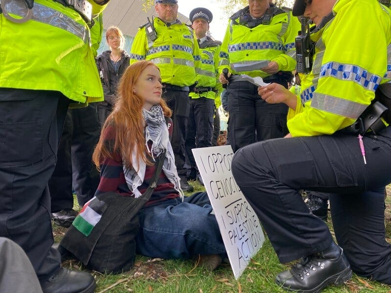 A woman holding a sign surrounded by police