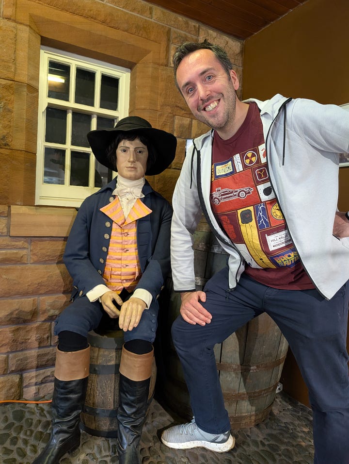 James posing beside a waxwork of Robert Burns, then an apple and kiwi gateau with colourful sprinkes, in a plastic container