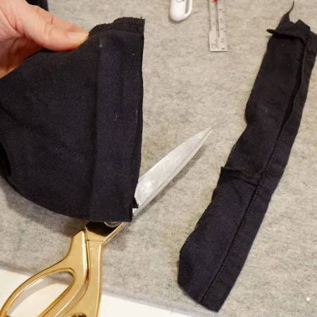 cutting of the excess fabric of pants that are going to be shortened and hemmed
