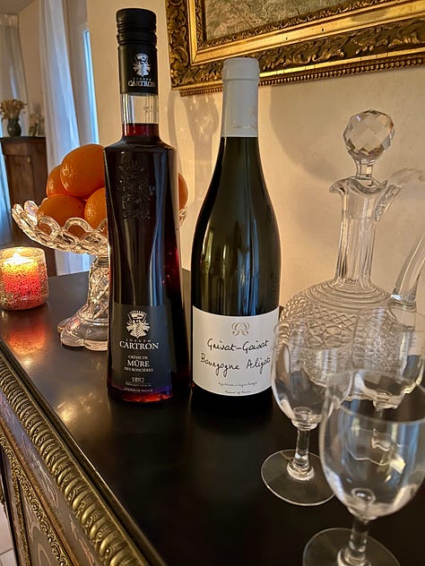 French wines and fruit syrups for making a kir cocktail, along with bottles and glasses