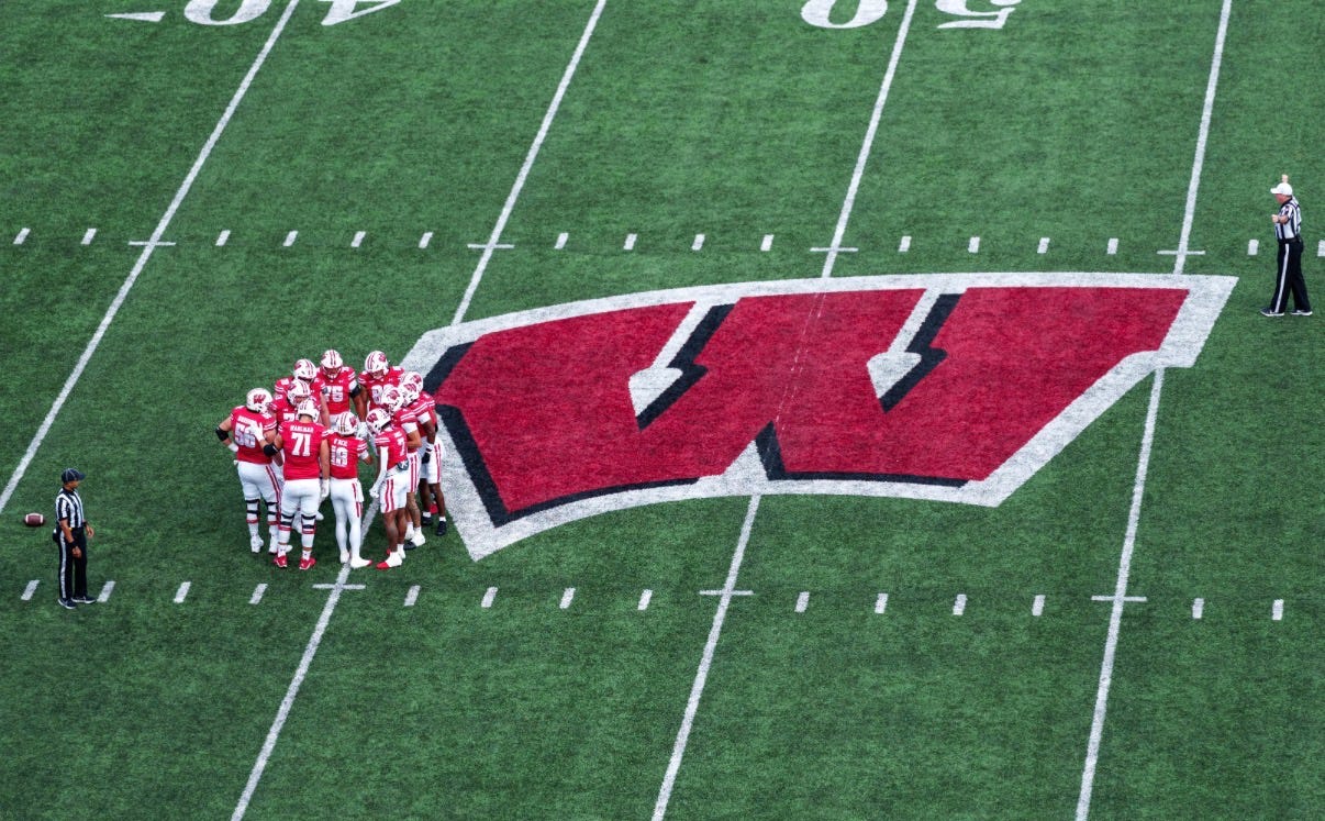 Wisconsin Badgers offense huddles near midfield during a game at Camp Randall Stadium. 