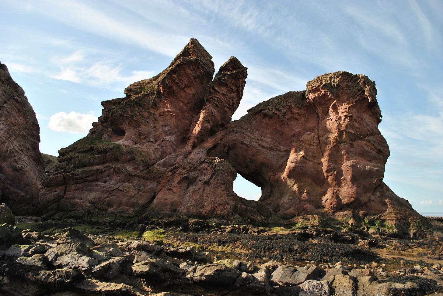 Sea stack with hole through, red sandstone
