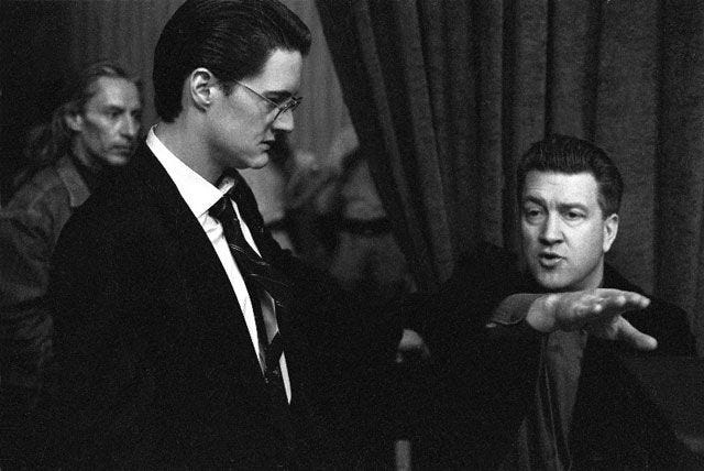 This may contain: black and white photo of two men in suits pointing at something on the other side
