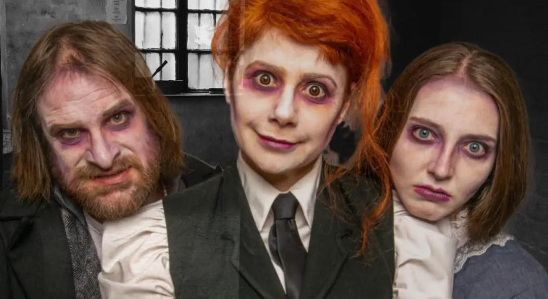 Three people - a man and two women - with purple bruised makeup and black and white suits staring into the camera Three people - a man and two women - with purple bruised makeup and black and white suits staring into the camera