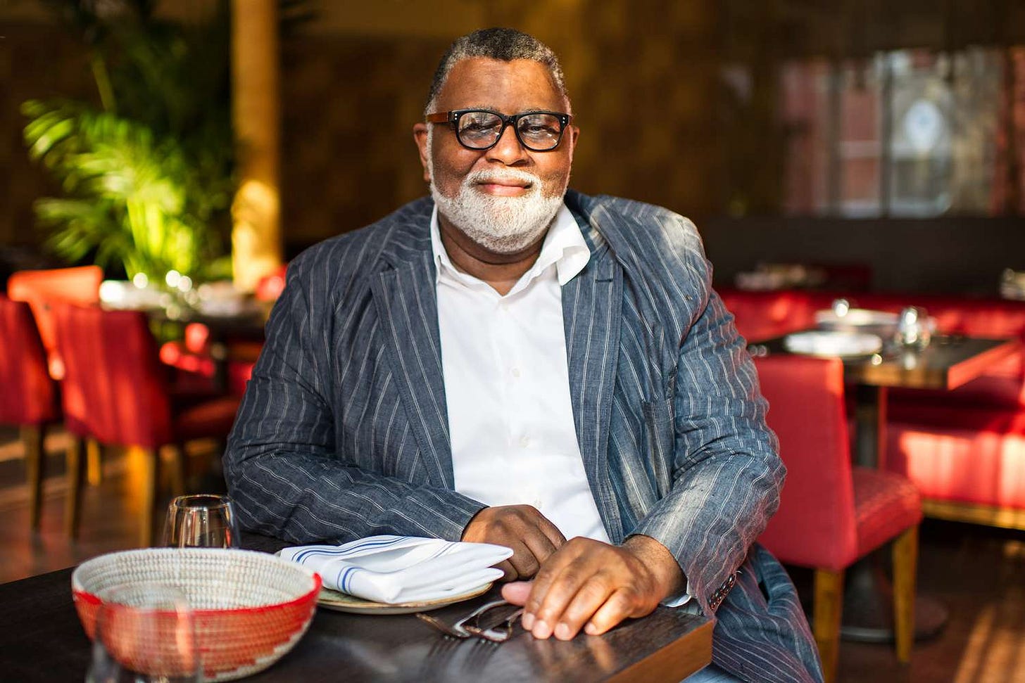 Alexander Smalls, a Black male chef, sits at a restaurant table