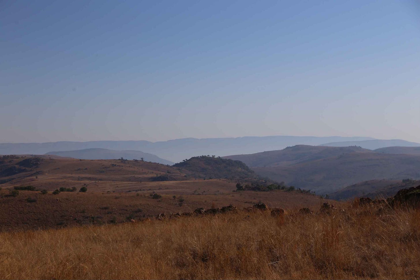 Blue low mountains in the distance with grass-covered hills in foreground