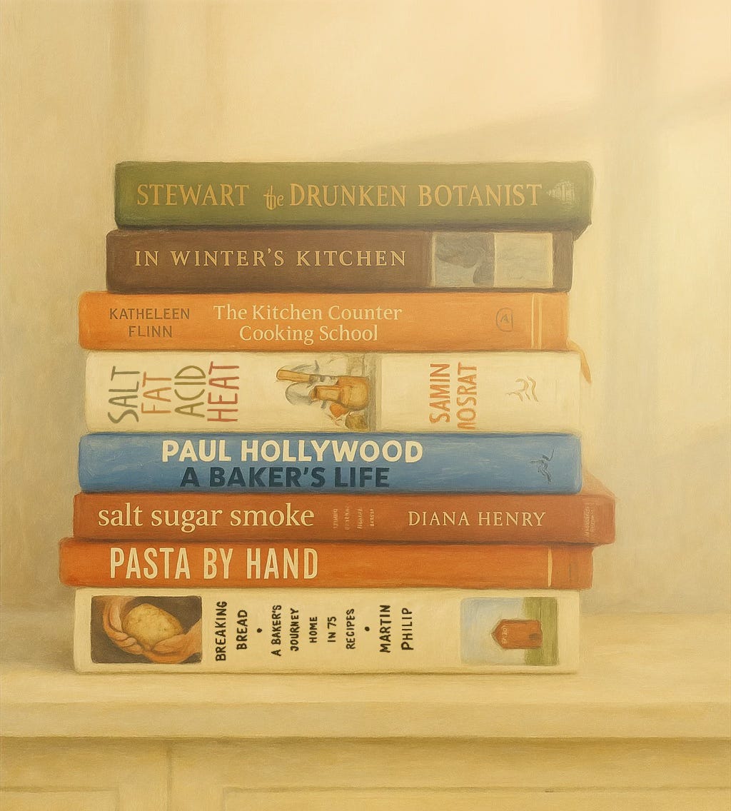 A painted stack of cookbooks on a soft-lit shelf, including titles by Samin Nosrat, Paul Hollywood, Diana Henry, Kathleen Flinn, and Martin Philip.