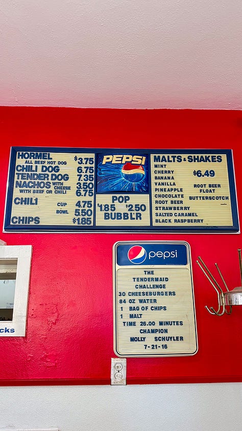 View of line outside of the door. Employee scooping ground beef onto a bun. Closeup of the menu on an old school board.