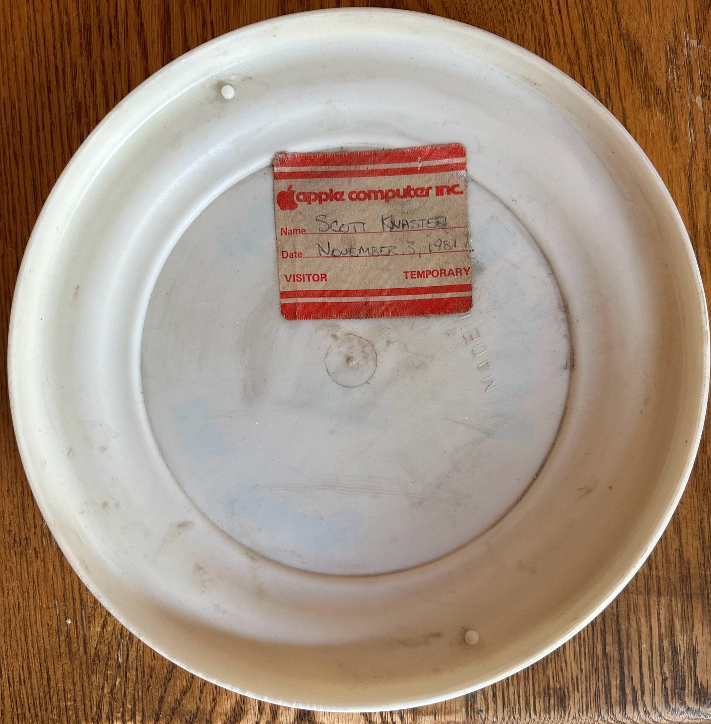 Back side of frisbee with a red Apple visitor badge that says Scott Knaster and the date of November 3, 1981. The badges were a different color each day, so you couldn't reuse a badge on another day.
