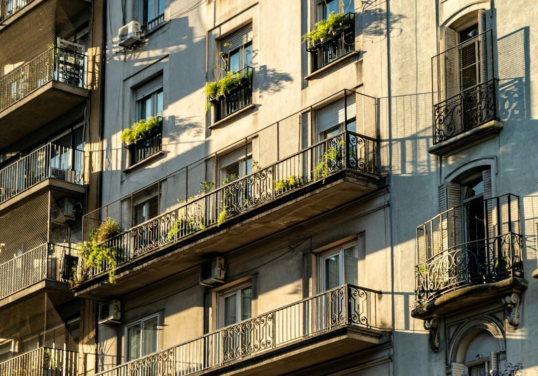 Apartment building balconies with plants and shadows.