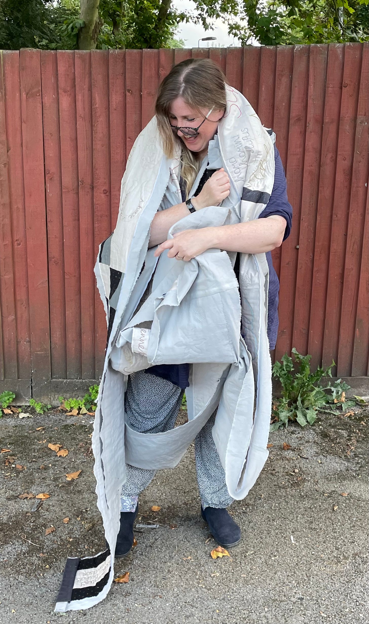 A white woman wrapped in a large piece of quilting