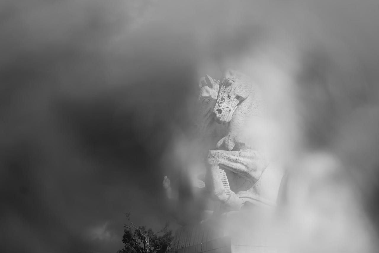 a statue of two horses is seen through fog