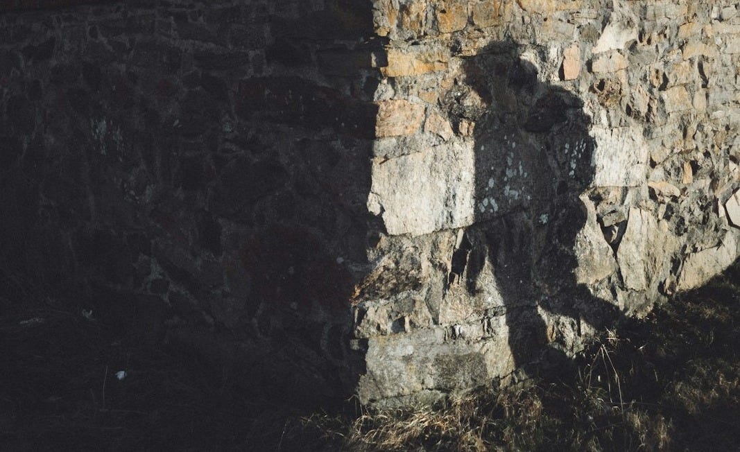 a shadow of a person standing next to a stone wall a shadow of a person standing next to a stone wall