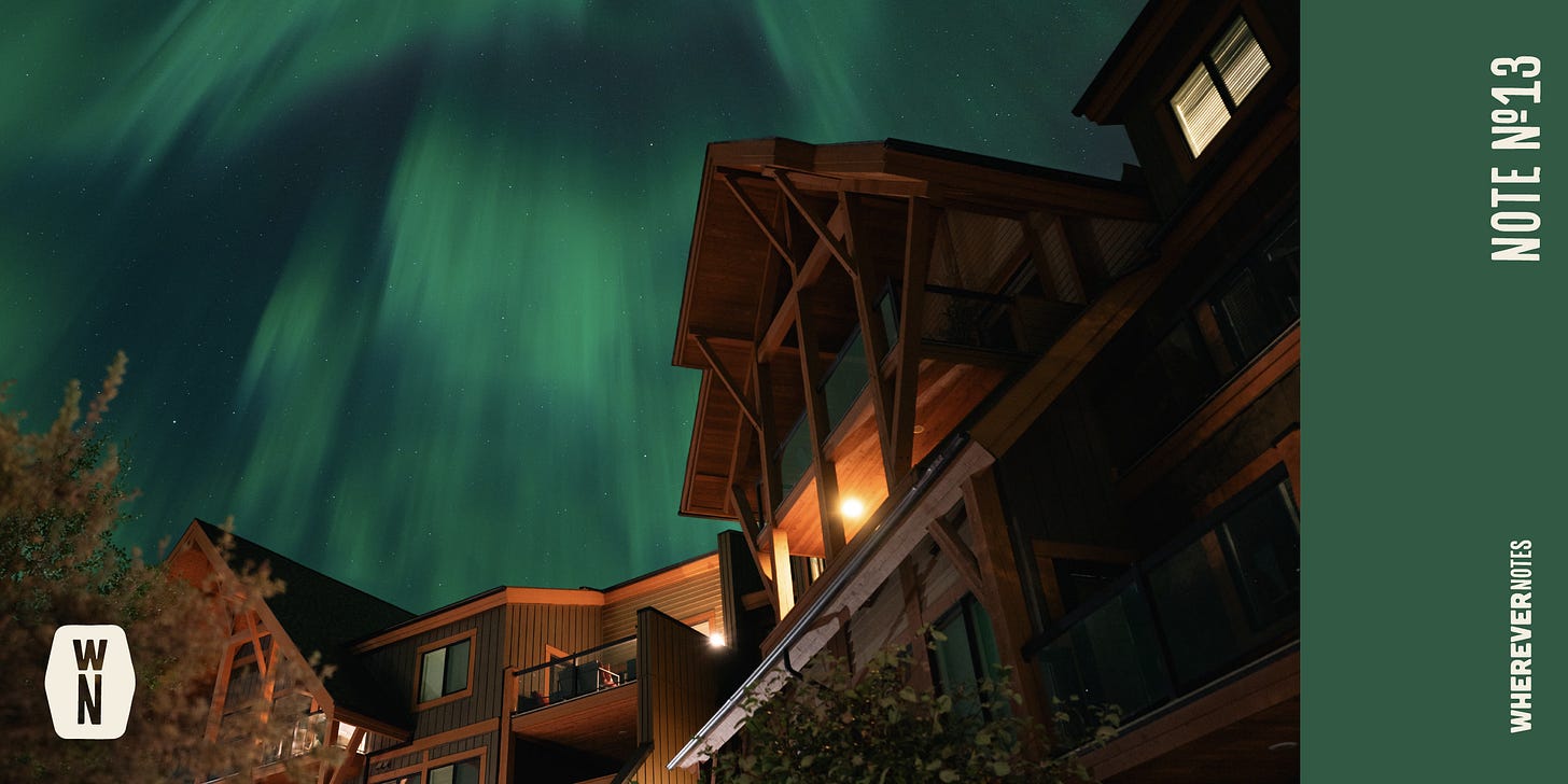 Green northern lights and dark night sky above lodge.