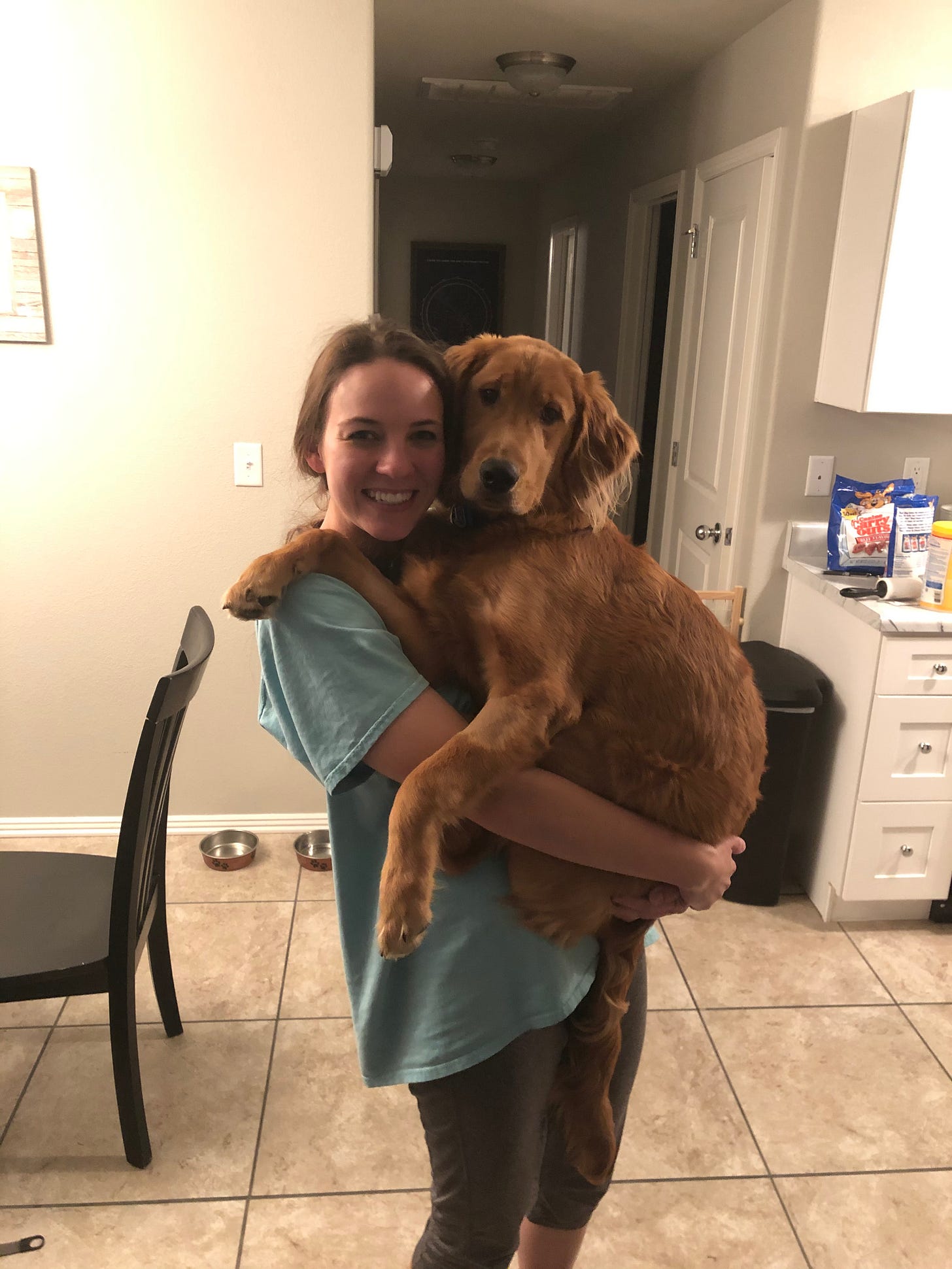 A woman holds her golden retriever in her arms