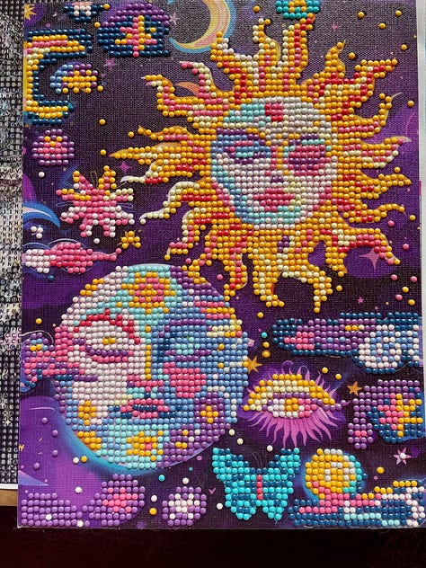 3 photos of 'diamond art' creations where small plastic gemstones in varying colours are slowly added to paper in a specific pattern. It is methodical and soothing but also fun and colourful art. The photos feature an irredescent fairy, a colourful moon and sun illustration with stars. planets and butterflies for decoration, plus a colourful fruit scene with watermelon, dragonfruit, cherries, bananas, oranges and strawberries, with the sticking pen tool in view.