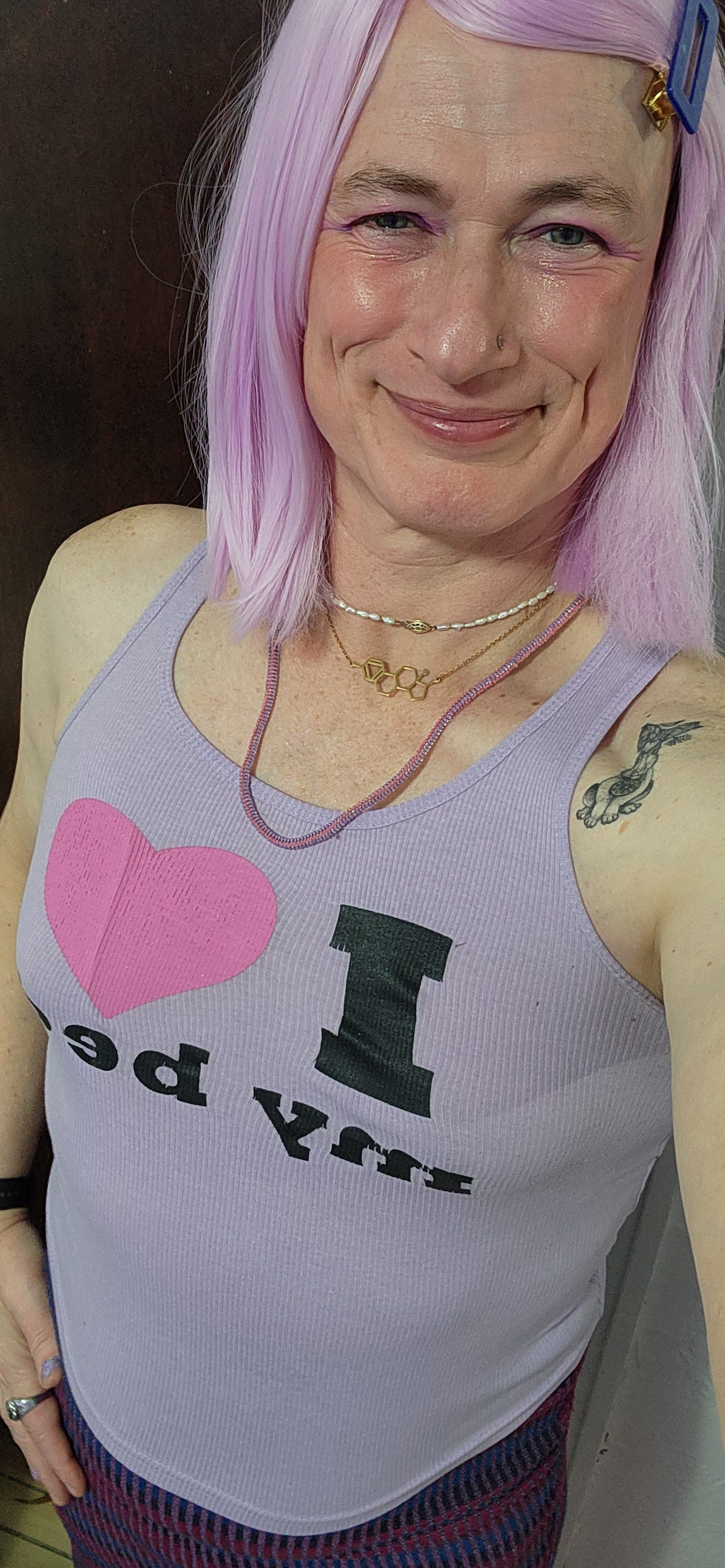 Davi Gray wearing pink hair, blue barrette, 3 necklaces, and a purple T-shirt which says "I ❤️ my bed"