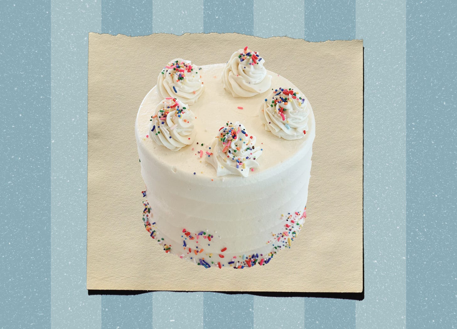 A vanilla birthday cake with white frosting and swirls dolloped along the top with colorful sprinkles