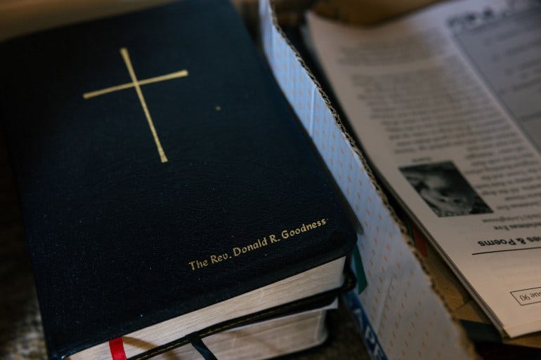 An up-close photograph of a Bible that has the name "The Rev. Donald R. Goodness" embossed on the front below a large gold cross. An up-close photograph of a Bible that has the name "The Rev. Donald R. Goodness" embossed on the front below a large gold cross.