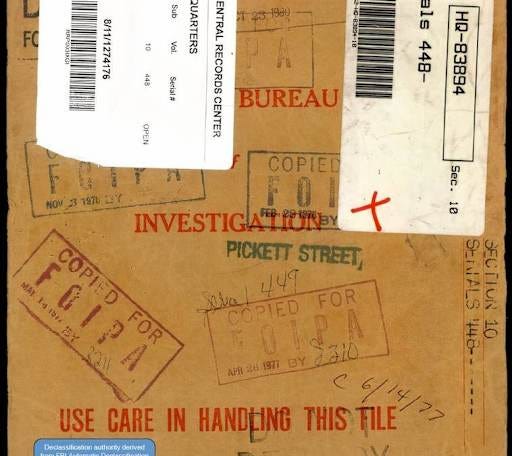 A close-up shot of a physical manila document folder with a large red Classified stamp on the front, representing archival government records.