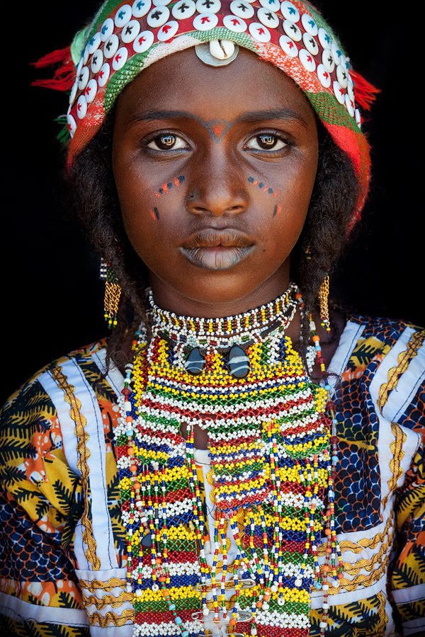Lovette Jallow wearing yellow during a cultural gathering—scarification visible as a marker of Fulani ancestral lineage and belonging.