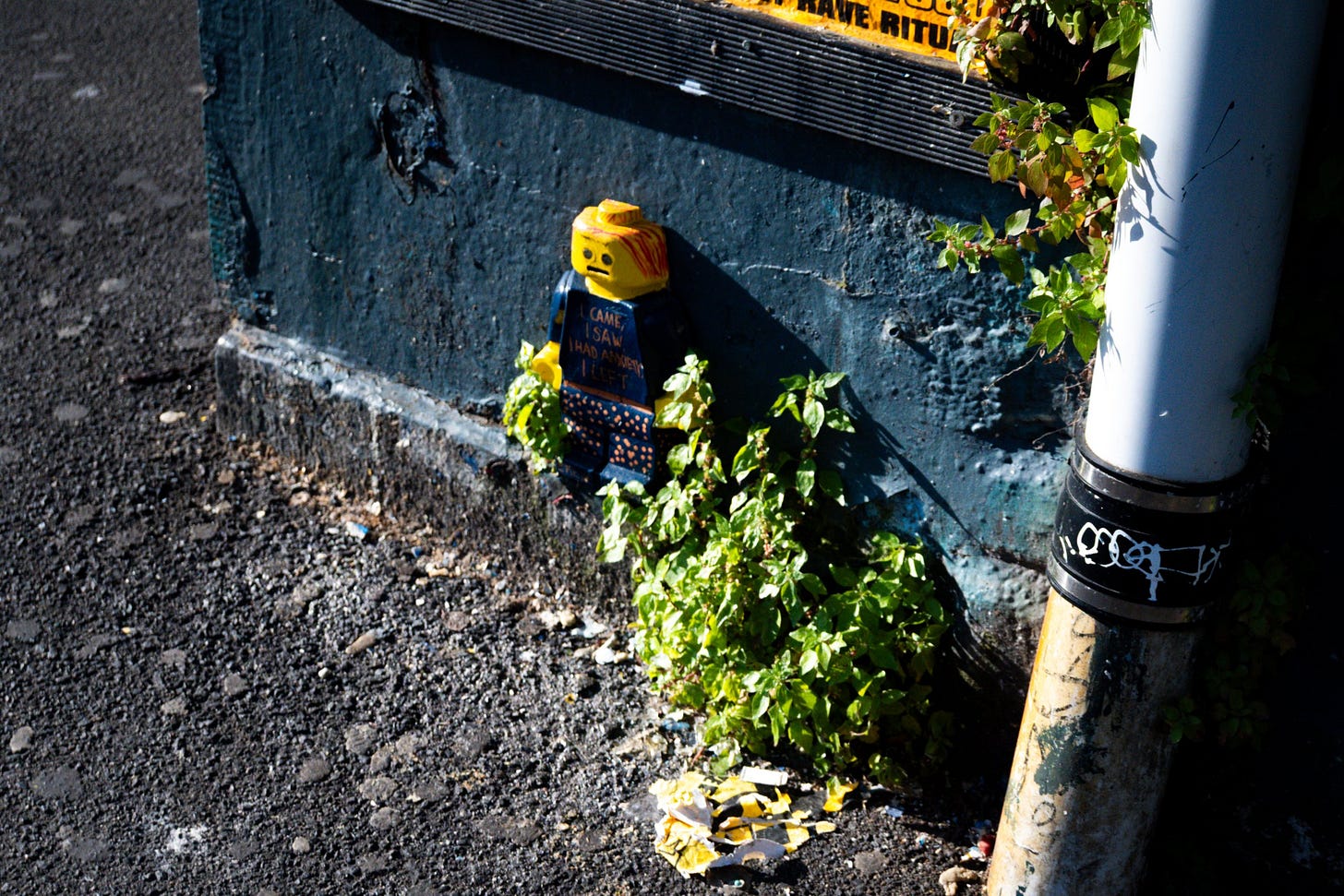 Toy Figure Among Urban Graffiti and Plants